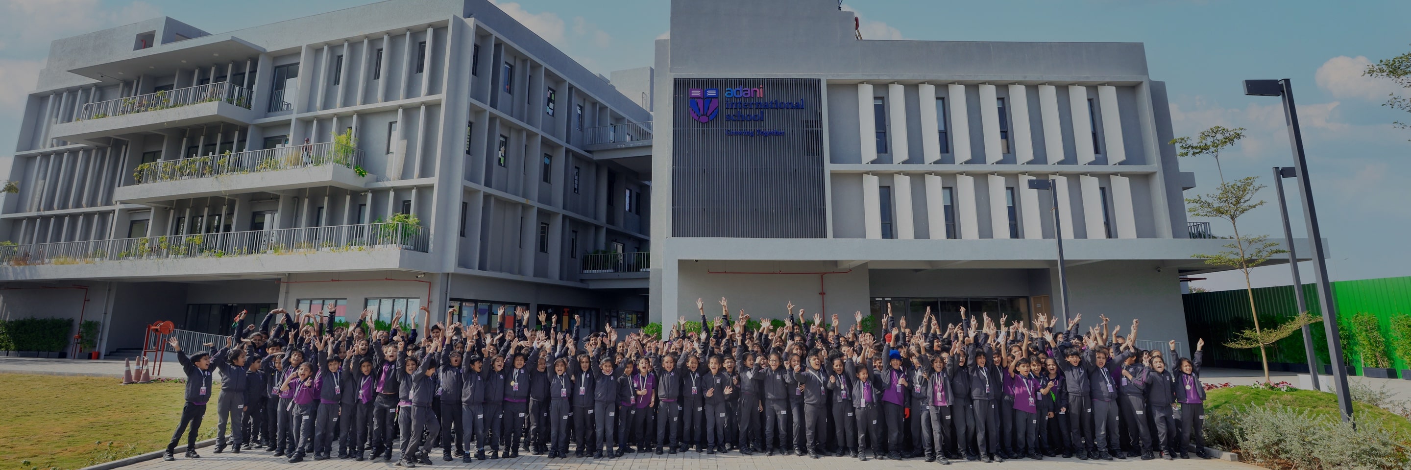 Students cheering in front of Adani International School's building